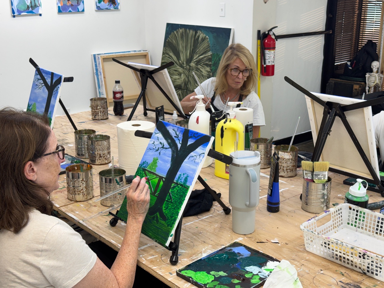 A small, steady group painting together at the table on a class evening.