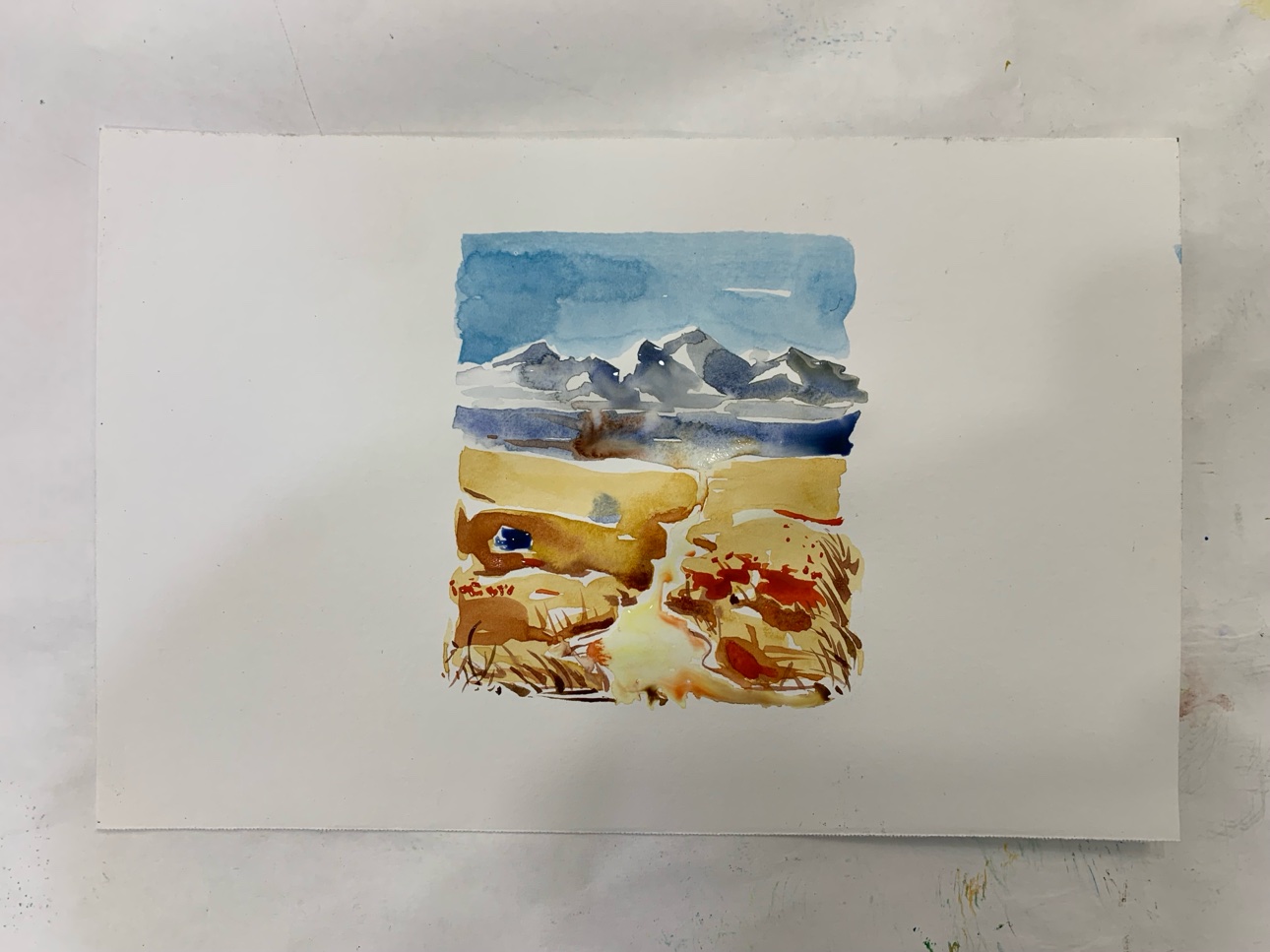 A small watercolor landscape with mountains. The white in the painting is the paper itself.